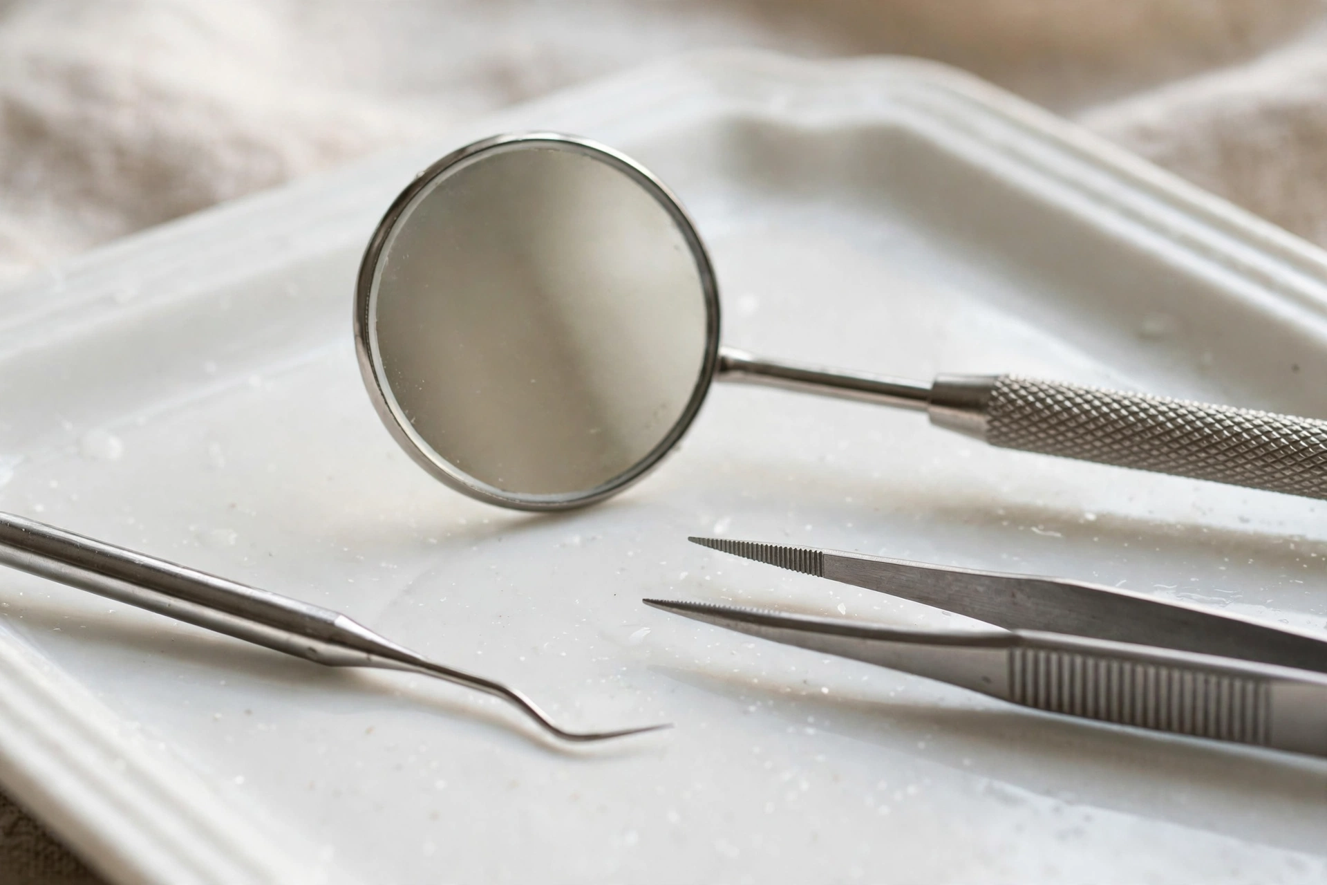 Dental mouth mirror and polished instruments on a porcelain tray